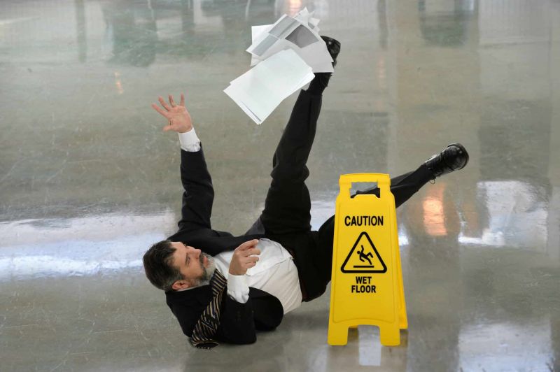 Man in a suit falling to the ground with his arms and legs in the air and papers falling from his hands.