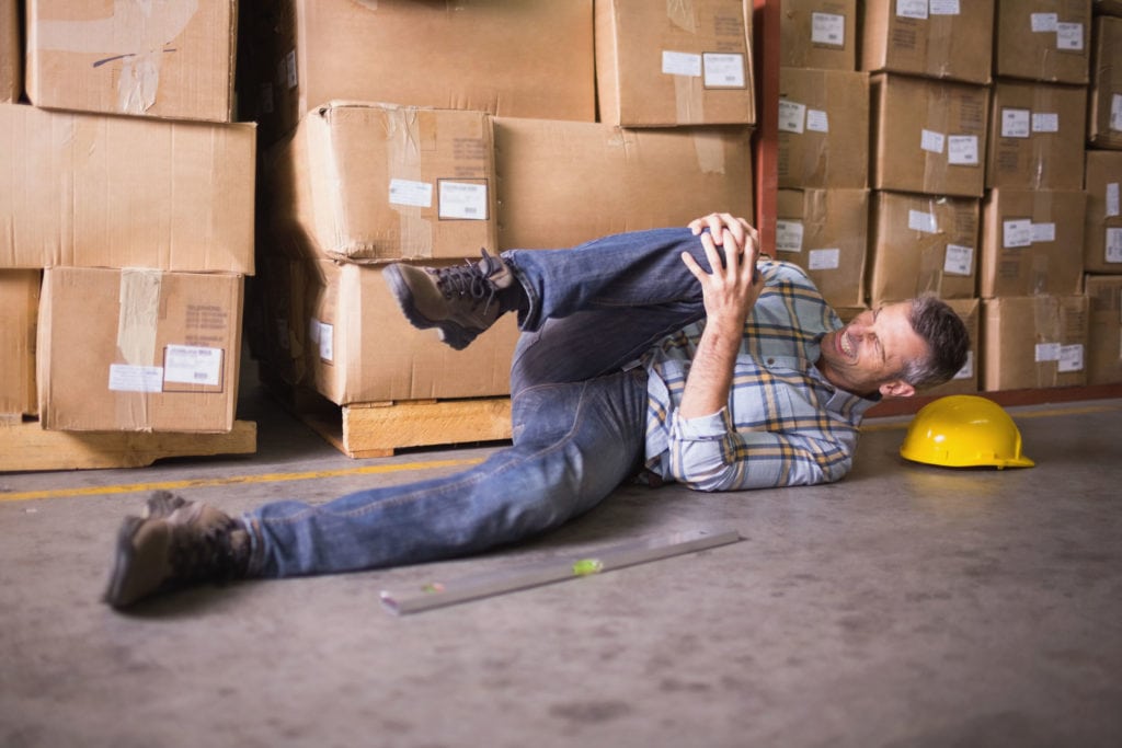 personal injury at work with man laying on floor holding his knee