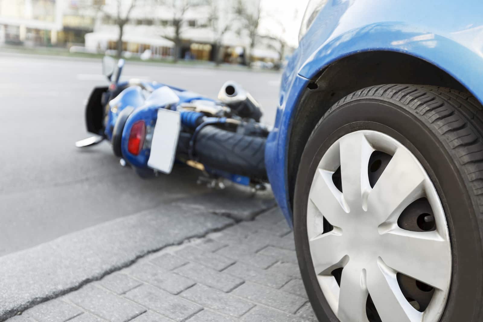 Motorcycle laying on the ground after being hit by a blue car. Call Peter's Law Firm, Council Bluffs