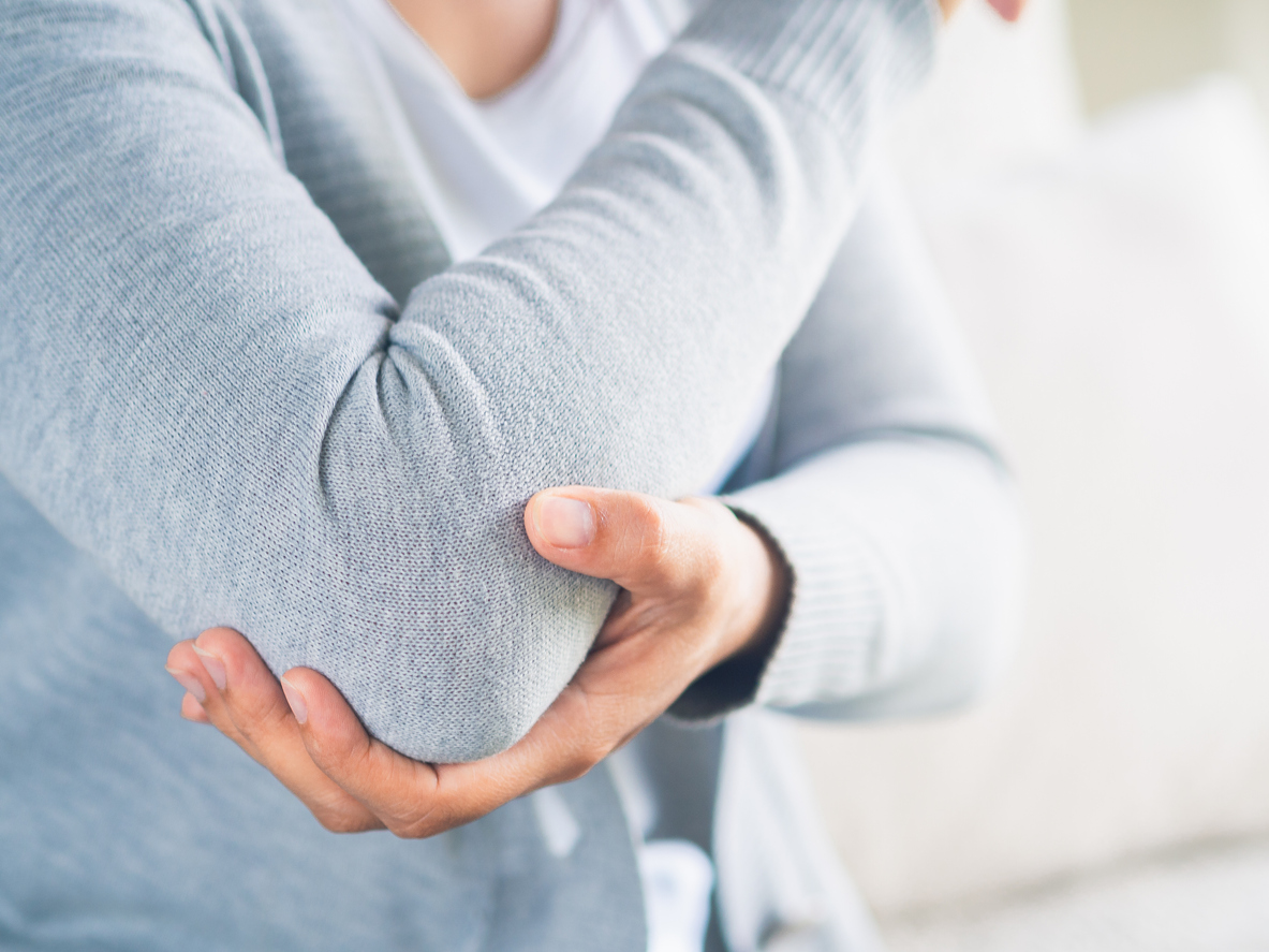 woman holds injured elbow